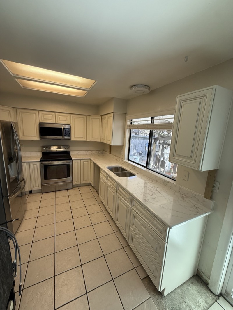 Antique white raised-panel kitchen with marble-look quartz countertops