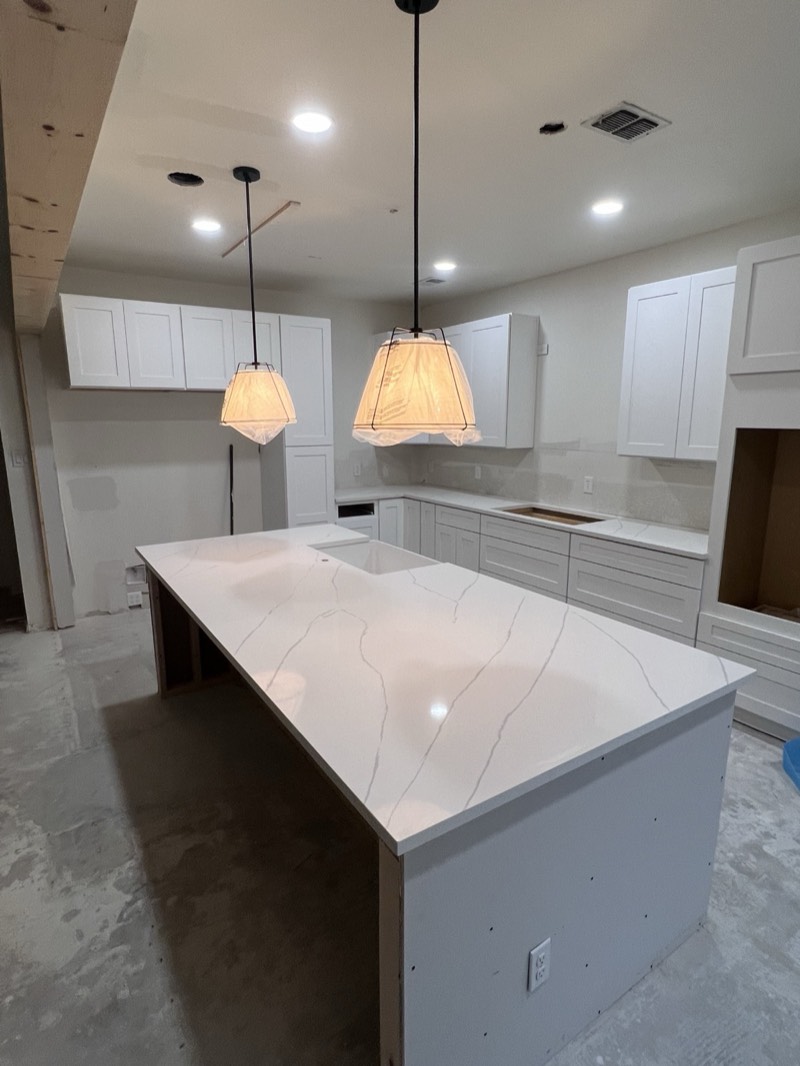 Cocina shaker blanca con isla de cuarzo tipo Calacatta e iluminación colgante