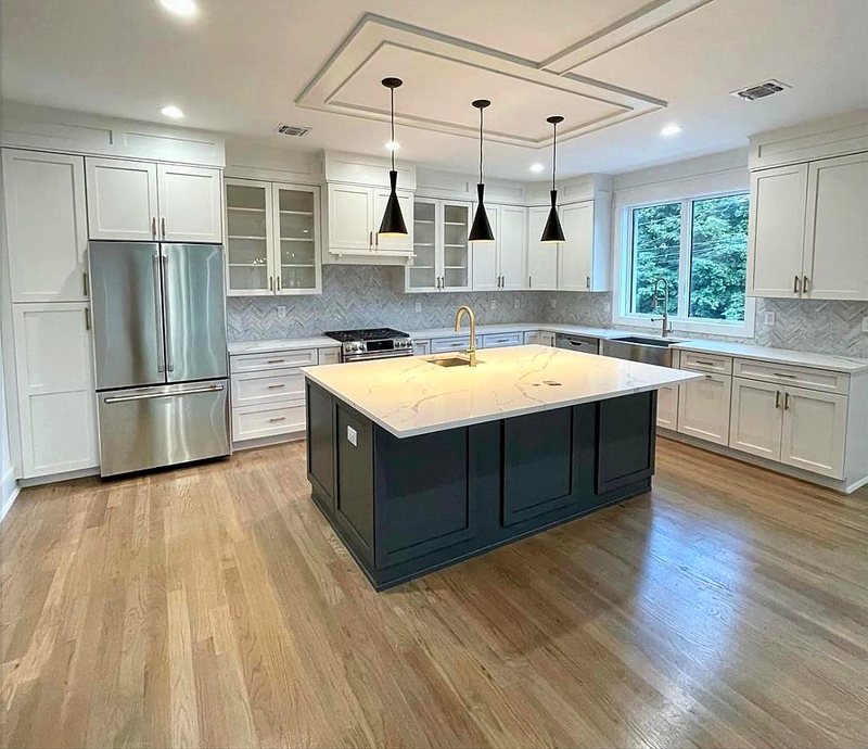 White shaker kitchen with a navy blue island, quartz countertop and herringbone tile backsplash