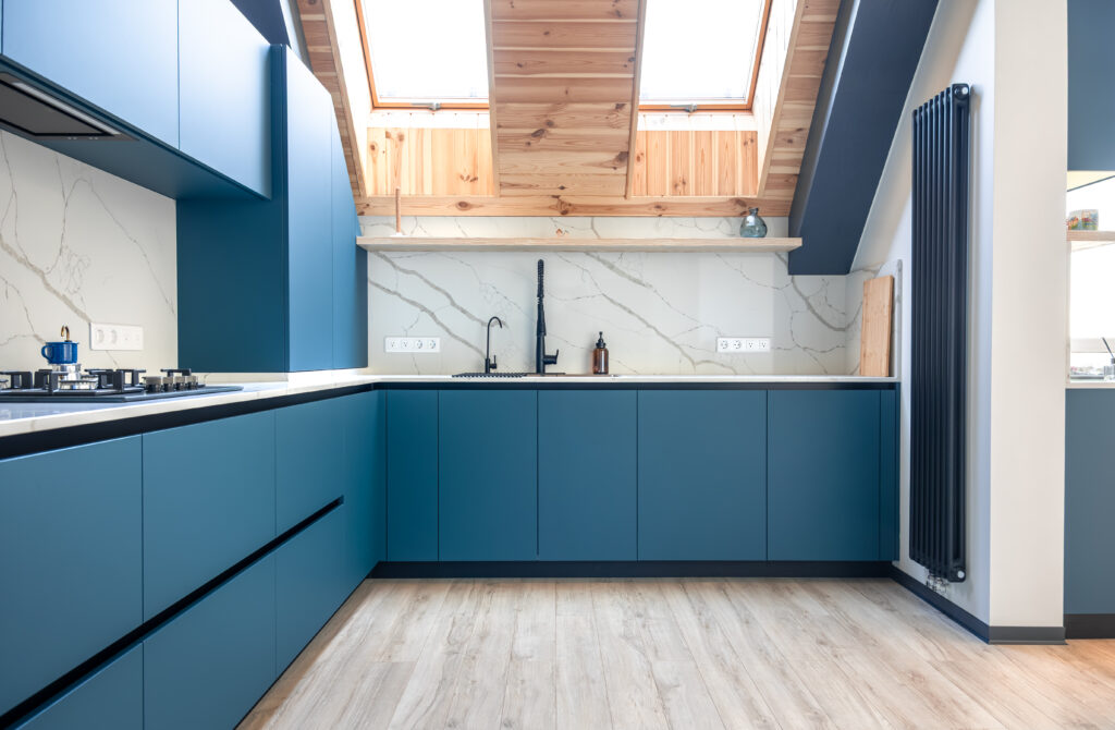 kitchen remodeler and cabinet installer from San Antonio- Corner attic kitchen with matte blue cabinets, light wood accents, and Scandinavian aesthetic. Bright, ergonomic and stylish cooking area with natural light.