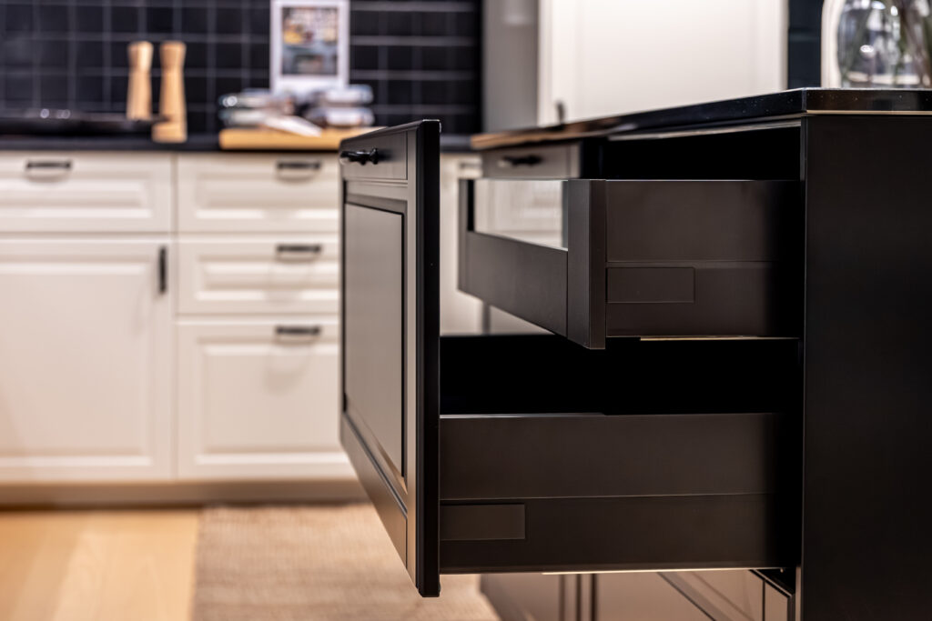 custom kitchen cabinets in 2026-European dark wood kitchen cabinets- Side view of a pullout drawer in a dark island with soft bokeh of white cabinets behind. Clean living declutter mood for modern home decor and interior styling. 